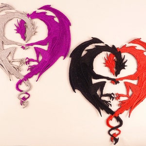 May include: Two embroidered patches of dragons intertwined in a heart shape. One patch is silver and purple, the other is black and red.