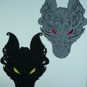 May include: Two embroidered iron-on patches of wolf heads with intricate swirling designs. The wolf on the left has black fur and yellow eyes, while the wolf on the right has grey fur and red eyes.
