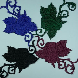 May include: Four embroidered iron-on patches featuring roses with intricate details. The roses are in shades of blue, green, black, and burgundy.
