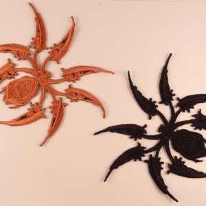 Peut inclure: Deux patchs brodés thermocollants en forme d'araignée stylisée. Un patch est brun et l'autre est noir.