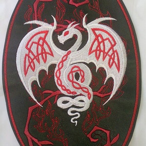 Peut inclure: Un dragon blanc brodé avec des accents rouges sur un patch ovale noir. Le dragon est enroulé autour d'une branche avec des feuilles rouges.