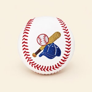 Op de afbeelding: Een witte honkbal met rode stiksels langs de naden. Het midden van de bal toont een geborduurd ontwerp van een beige houten honkbalknuppel gekruist met een kleine honkbal en een blauwe honkbalpet met witte details.