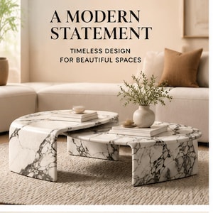 Könnte beinhalten: Ein Set aus zwei ineinandergreifenden Couchtischen mit einer weißen Marmoroberfläche und markanter schwarzer Maserung. Die Tische haben ein geschwungenes Wasserfall-Design. Der Text auf dem Bild lautet: A MODERN STATEMENT, TIMELESS DESIGN FOR BEAUTIFUL SPACES.