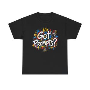 以下が含まれることがあります： 胸元にカラフルなグラフィックプリントが施された黒の半袖Tシャツ。デザインには白で「Got Prompts?」という文字が描かれ、鮮やかな赤、青、黄色のペンキの飛沫、黄色の王冠、電球、ロボットのアイコンが周囲を囲んでいます。