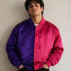 Puede incluir: Una chaqueta tipo bomber de dos tonos con un diseño dividido, con el lado derecho de color morado intenso y el lado izquierdo de color rosa vibrante. La chaqueta está confeccionada en un material satinado liso con cuello y puños acanalados.