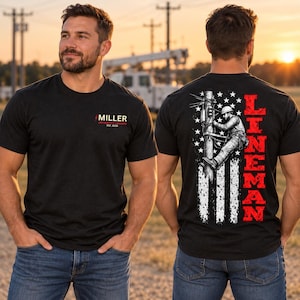 May include: A black short-sleeve t-shirt featuring a small logo on the front chest with the text MILLER APPRENTICE LINEMAN EST. 2026. The back displays a large graphic of a utility worker on a pole over a distressed American flag and the word LINEMAN.