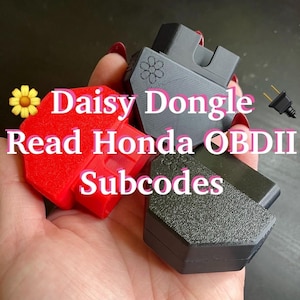 May include: Three OBDII diagnostic dongles in red and black, each featuring a small daisy icon embossed on the surface. The text Daisy Dongle Read Honda OBDII Subcodes is overlaid on the image, which shows the devices with a connector port.