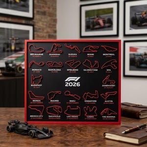 May include: A square wall art piece with a red frame featuring a black background displaying the 2026 Formula 1 race calendar. It includes twenty-four red 3D track outlines with city names and dates printed in white text below each circuit.