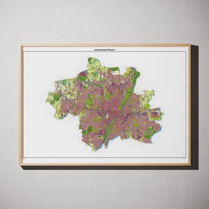 May include: A framed map of Munich, Germany, titled Landeshauptstadt München at the top. The map features a detailed urban layout with purple and green color blocks representing city infrastructure, roads, and green spaces on a white background.