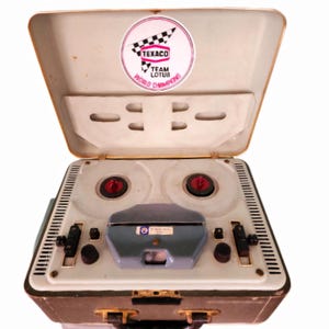 May include: A vintage reel-to-reel tape recorder in a white and green case with a Texaco Team Lotus World Champions sticker on the lid. The recorder has two reels, a control panel, and a microphone.