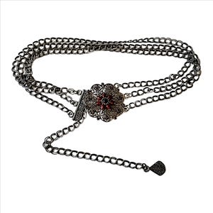 May include: A silver-toned chain belt with a decorative floral buckle featuring red accents. The belt has three parallel chains and a dangling chain with a decorative end. The belt is designed to be worn around the waist.