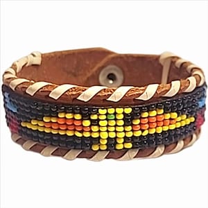 May include: A brown leather bracelet with a beaded design. The bracelet features a central band of black beads with a colorful pattern of yellow, orange, and red beads. The edges are trimmed with cream-colored stitching.