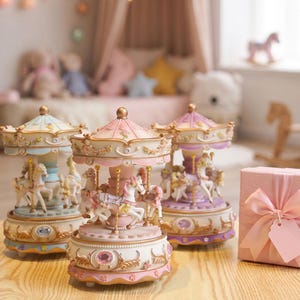 May include: Three decorative carousel music boxes featuring white horses with gold accents, pastel-colored roofs, and ornate bases with embedded faux gems. Each carousel is detailed with floral motifs and stands on a light-colored wooden surface.