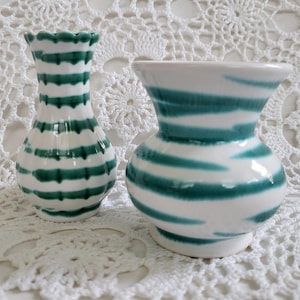 May include: Two ceramic vases with green and white striped patterns. The smaller vase has a scalloped rim. The larger vase has a wider base and a more rounded shape.