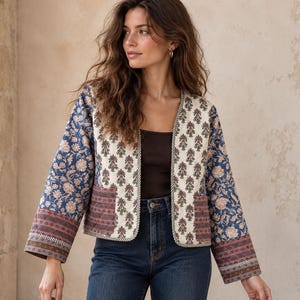 Puede incluir: Una chaqueta acolchada con una mezcla de patrones florales y geométricos en tonos azul, crema y marrón. La chaqueta tiene mangas largas, frente abierto y dos bolsillos delanteros con un borde a rayas en contraste en el dobladillo y puños.