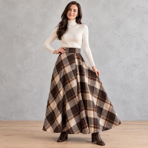 Könnte beinhalten: Ein langer Rock mit hoher Taille und einem Karomuster in Braun, Beige und Creme mit einer weit ausgestellten Silhouette. Der Rock wird mit einem langärmeligen, cremefarbenen Rollkragenpullover und dunkelbraunen Lederstiefeletten kombiniert.