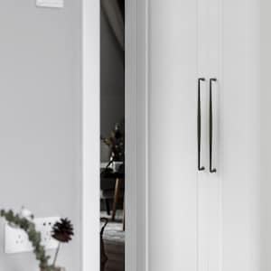 May include: A pair of long, slender, dark-toned metal door handles mounted vertically on a white paneled door. The handles feature a simple, straight design with subtle curves at the top and bottom attachment points, contrasting against the white surface.
