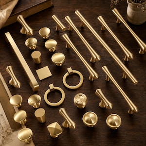 Può includere: Una collezione di ferramenta per mobili color ottone che include vari tiranti per cassetti, maniglie a T, pomelli rotondi, pomelli quadrati e tiranti ad anello. L'assortimento presenta finiture metalliche spazzolate e lisce in varie forme.