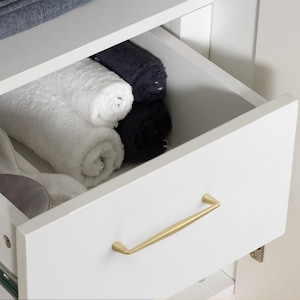 May include: A white drawer with a gold-toned metal handle, partially open to reveal two white rolled towels and two dark charcoal rolled towels stored inside the compartment. The drawer front is smooth and features a minimalist horizontal pull.
