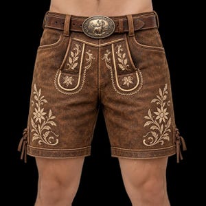 Puede incluir: Pantalones cortos de cuero marrón con intrincados bordados florales de color crema en los paneles frontales y bolsillos. Incluyen un cinturón de cuero marrón a juego con una hebilla metálica ovalada grande y ornamentada con relieve.