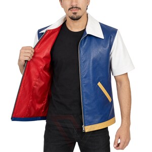 Könnte beinhalten: Eine kurzärmelige Jacke mit blauer Vorderseite, weißen Ärmeln und Kragen sowie einem leuchtend roten Innenfutter. Das Kleidungsstück verfügt über einen silberfarbenen Frontreißverschluss, ein gelbes diagonales Taschendetail und einen gelben Saum.