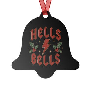 Può includere: Un ornamento nero a forma di campana con il testo rosso HELLS BELLS, un fulmine rosso centrale, foglie di agrifoglio verdi e bacche rosse, sospeso da un sottile nastro rosso per essere appeso a un albero o a un espositore.