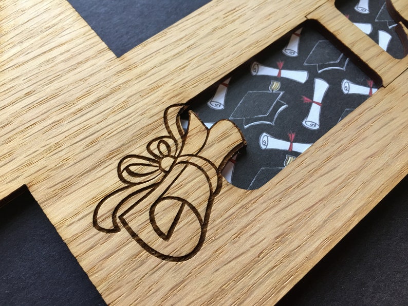 Peut inclure: Cadre photo en bois sur le th&egrave;me de la remise de dipl&ocirc;mes, avec un motif de dipl&ocirc;me et de n&oelig;ud grav&eacute; au laser. Le cadre comporte des ouvertures pour plusieurs photos, avec un fond &agrave; motifs de chapeaux et de dipl&ocirc;mes de fin d'&eacute;tudes.