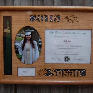 Peut inclure: Un cadre de dipl&ocirc;me en bois avec une photo, un dipl&ocirc;me et un pompon. Le cadre comprend l'ann&eacute;e "2016" et le nom "Susan". Le dipl&ocirc;me est de l'Ivy Tech Community College.