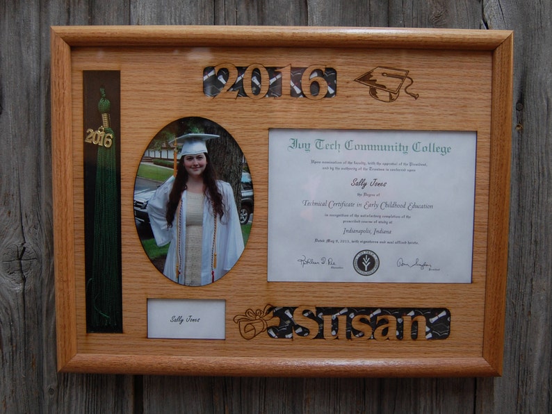 Peut inclure: Un cadre de dipl&ocirc;me en bois avec une photo, un dipl&ocirc;me et un pompon. Le cadre comprend l'ann&eacute;e "2016" et le nom "Susan". Le dipl&ocirc;me est de l'Ivy Tech Community College.