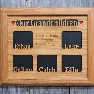 Puede incluir: Un marco de fotos rectangular de madera marrón claro con cinco aberturas cuadradas. El marco presenta el texto cortado con láser Our Grandchildren, dos corazones rojos y la frase grabada Precious Hearts, Priceless Grins 'N Giggles. Los nombres Ethan, Luke, Galina, Caleb y Ella están recortados debajo de las ranuras para fotos.