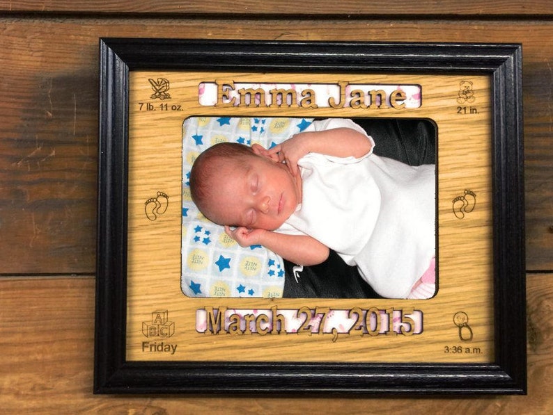 May include: A wooden photo frame with a black border, featuring a baby girl sleeping in a white onesie. The frame includes the baby's name "Emma Jane", birth date "March 27, 2015", and birth stats: 7 lb. 11 oz. and 21 in.