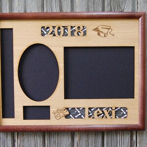 Peut inclure: Cadre photo de graduation en bois avec un int&eacute;rieur en bois clair et une bordure en bois fonc&eacute;. Le cadre comporte des d&eacute;coupes pour les photos, l'ann&eacute;e "2018", une toque de dipl&ocirc;m&eacute; et le nom "Lexi". Le fond des d&eacute;coupes est un tissu &agrave; motifs.