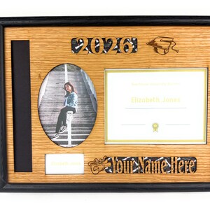Peut inclure: Un cadre de dipl&ocirc;me en bois avec une bordure noire. Il comprend un espace photo, un espace pour le dipl&ocirc;me et des zones de personnalisation. Le cadre comprend l'ann&eacute;e "2026" et le texte "Your Name Here".