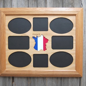 May include: A light-colored wooden collage picture frame featuring eight black mat openings, including four ovals and four rectangles. In the center, a cutout of the map of France displays the blue, white, and red flag with the word FRANCE above it.