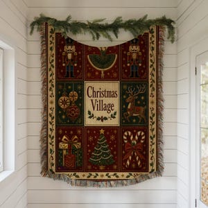 May include: A rectangular woven tapestry blanket featuring a grid of holiday imagery including nutcrackers, a ballerina, ornaments, a reindeer, a gift, a Christmas tree, and candy canes. The center panel displays the text Christmas Village.