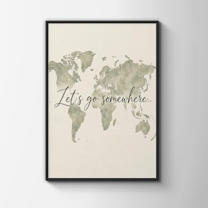 Puede incluir: Un cuadro decorativo con un mapa del mundo estilo acuarela en tonos verde salvia sobre un fondo crema. El texto "Let's go somewhere.." está escrito en una tipografía cursiva negra en el centro de la ilustración del mapa mundial.