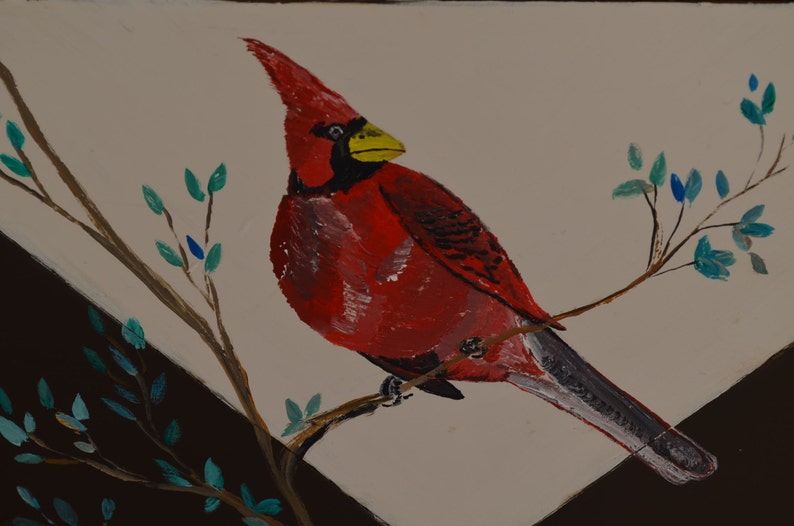 May include: A red cardinal bird with a yellow beak perched on a branch with green leaves. The bird is painted in a realistic style.
