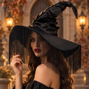 May include: A black witch hat featuring a tall, pointed, and slightly slumped crown with a wide brim. The brim is adorned with long, thin black fringe that hangs down over the face, creating a veil-like effect. The hat is made of a smooth, satin-like material.