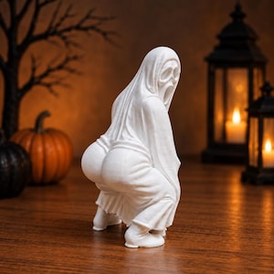Könnte beinhalten: Eine weiße Geisterfigur in einem Kapuzengewand mit einer Maske, die längliche Augen- und Mundöffnungen aufweist. Die Figur ist in einer hockenden Pose dargestellt, wobei die abgerundete Form des Unterkörpers betont wird.