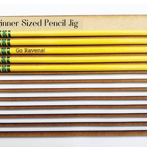 May include: Beginner Sized Pencil Jig with 10 slots for pencils. The jig is made of wood and has a light brown color. The text "Go Ravens!" is printed on the jig.