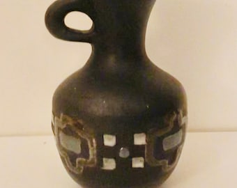 Può includere: Un piccolo vaso in ceramica nera con manico e design geometrico argento e bianco.