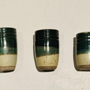 May include: Three ceramic mugs with a green and white glaze. The mugs are all the same size and shape, and they have a slightly textured finish.