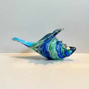 Peut inclure: Une sculpture en verre bleu, vert et blanc en forme de coquille. La sculpture est en verre soufflé et présente un motif tourbillonnant.