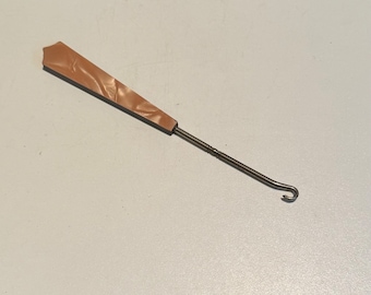 May include: A brown plastic handled crochet hook with a metal hook at the end.