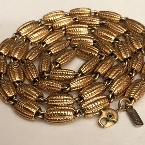May include: A gold-tone chain necklace with a textured, ridged design. The necklace is made by the brand "Monet".