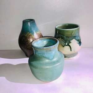 May include: Three ceramic vases in different shapes and sizes. The vases are glazed in shades of green, blue, and brown.