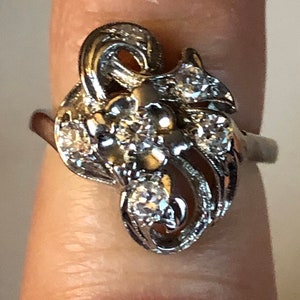 May include: A silver ring with a floral design and multiple small diamonds.