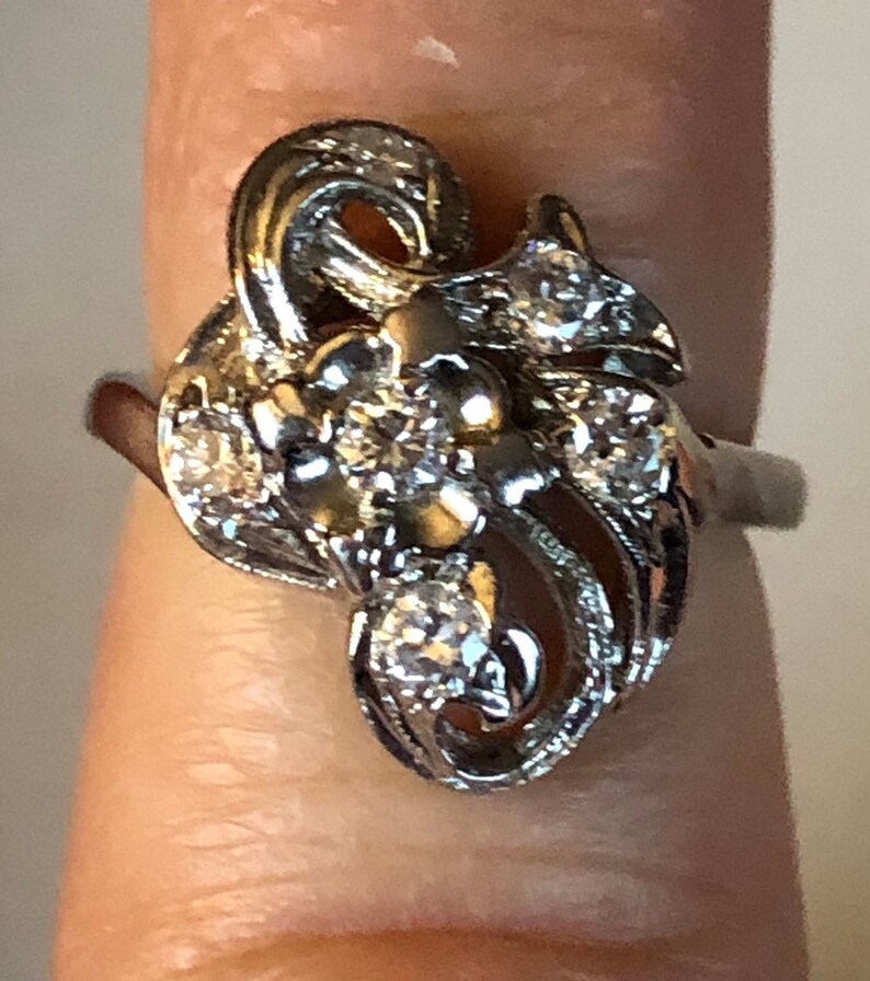May include: A silver ring with a floral design and multiple small diamonds.
