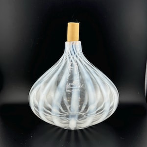 May include: A clear glass bottle with white stripes and a wooden stopper. The bottle is shaped like an onion and has a rounded bottom.
