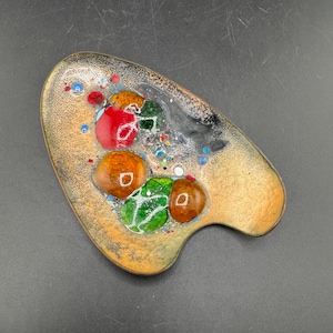 Könnte beinhalten: Abstrakte Emaille-Schale im modernen Stil der Mitte des Jahrhunderts in Palettenform. Die Schale hat eine Kupferbasis mit einem gesprenkelten, beigefarbenen Hintergrund. Bunte Emaille-Akzente in Rot, Orange, Grün und Blau.